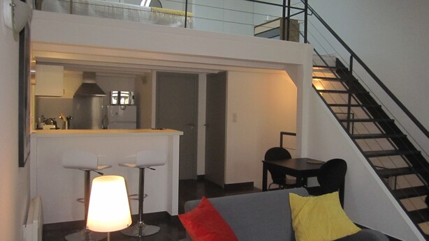 Un apartamento moderno con cocina, comedor y escalera.
