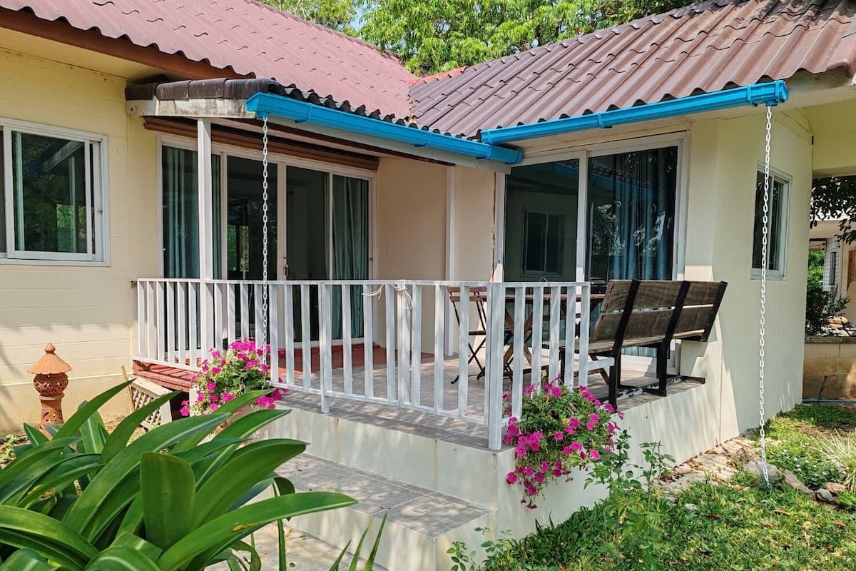 A house with a porch, a bench, and potted plants.