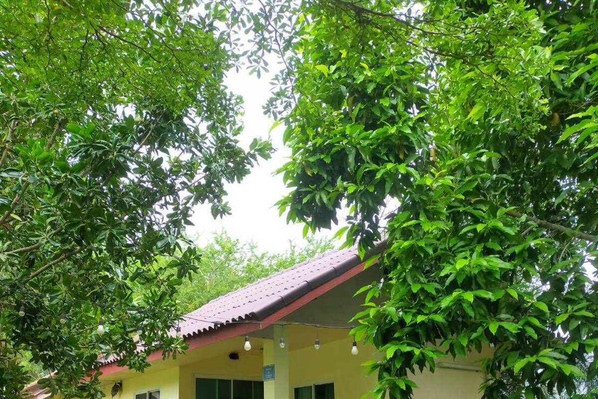 A single-story building with a red roof, a covered porch, and a small table and chair.