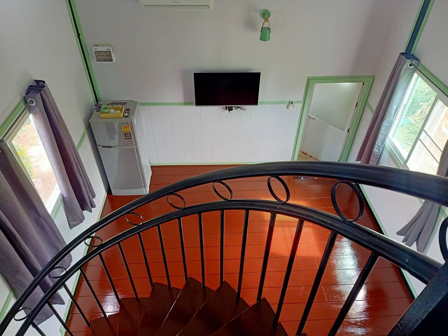 A staircase with a metal railing leading to a landing with a flat-screen TV mounted on the wall.