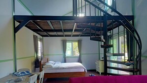 Un dormitorio con una cama litera, un escritorio con sillas, un sofá rosa y una ventana con cortinas.