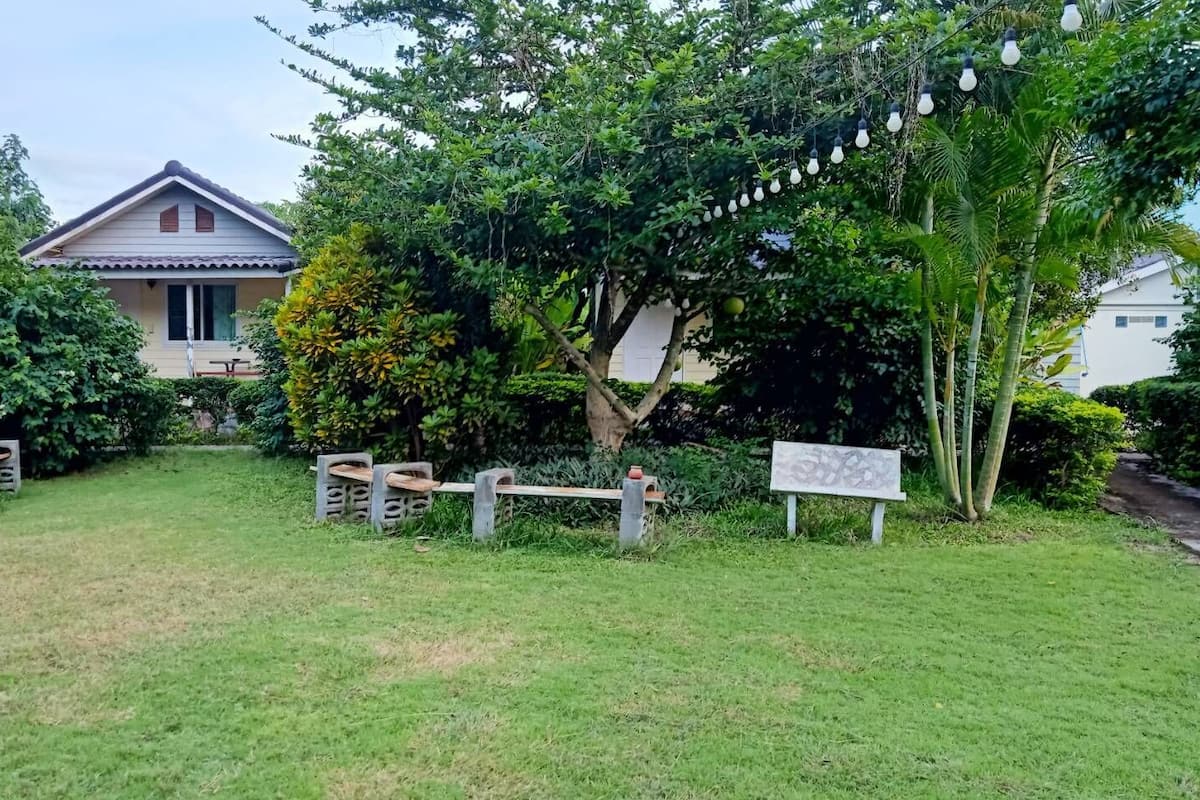 A garden with a house, outdoor seating, and a signboard.