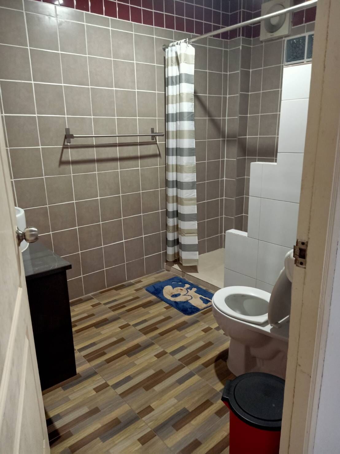 Un baño con ducha, inodoro y un lavamanos pequeño.