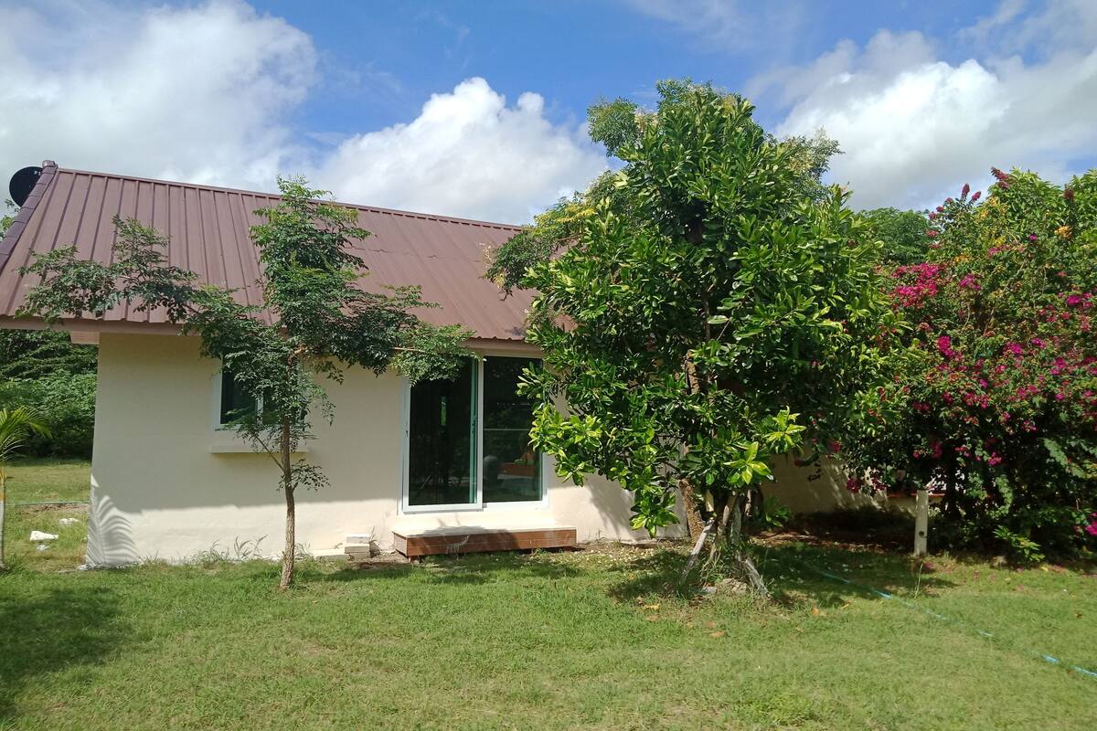 A single-story house with a brown roof, a small porch, and a well-maintained lawn.