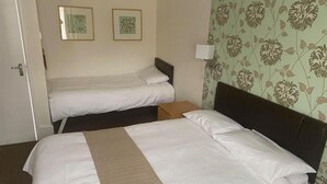 A hotel room with two beds, a door, and floral wallpaper. - The White Hart Hotel (Holsworthy)
