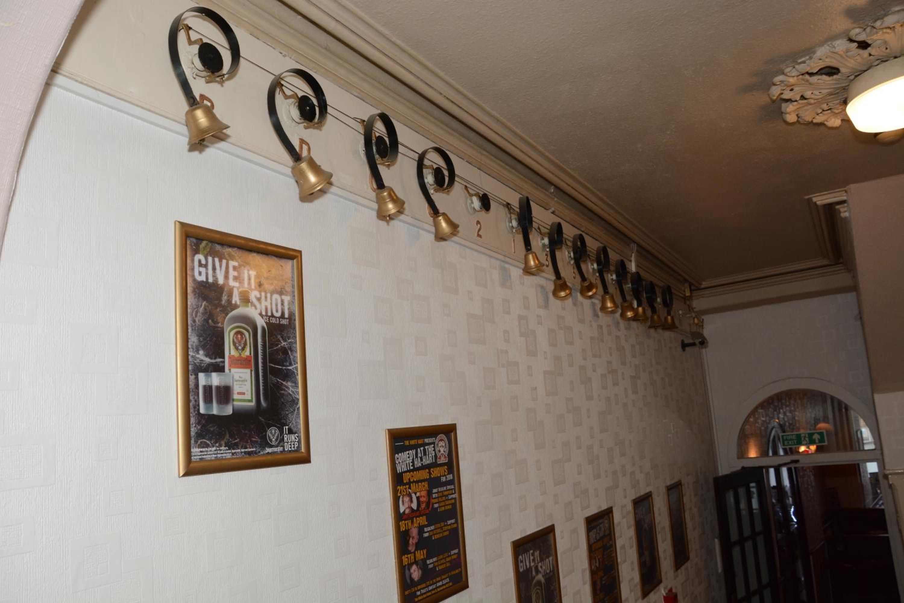 A wall with a series of bells and posters, including one for a comedy show.