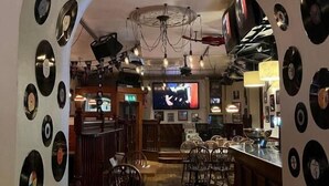 A bar area with wooden flooring, a counter, and a seating area with chairs. - The White Hart Hotel (Holsworthy)