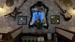 A room with a mirror, a guitar, and a drum set against a floral wallpaper. - The White Hart Hotel (Holsworthy)