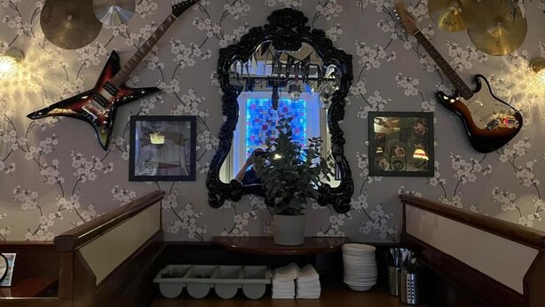 A room with a mirror, a guitar, and a drum set against a floral wallpaper. - The White Hart Hotel (Holsworthy)