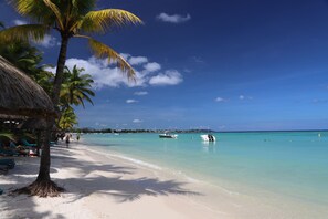 A beach with white sand, palm trees, and clear blue water.