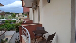Un balcón con mesa y sillas, con vistas a una zona residencial.