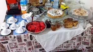Una mesa de buffet con diversos alimentos, entre ellos un pastel, pasteles y un tazón de sandía.