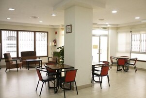 A hotel lobby with a reception desk, seating area, and large windows.