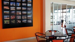 A modern office space with a large wall-mounted photo collage, a meeting table with chairs, and a glass partitioned area. - Hostal Villa (Chiclana de la Frontera)