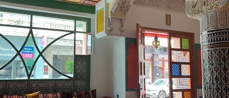 Ein Zimmer mit Glastisch, Wand mit Muster und Tür mit farbigen Glasfeldern.