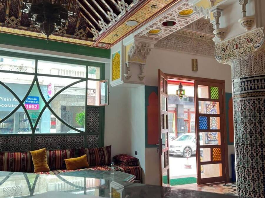 Una stanza con un tavolo in vetro, una parete decorata e una porta con pannelli di vetro colorato.