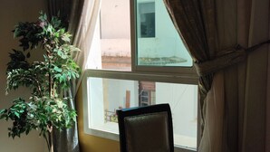 A room with a bed, a chair, a small table, and a potted plant by a window with curtains. - Hotel Maamoura (Casablanca)