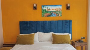 A bedroom with a large bed, a blue headboard, and a painting on the wall. - Hotel Maamoura (Casablanca)