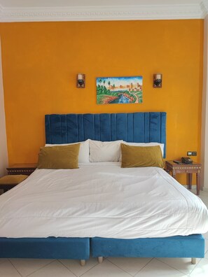 Un dormitorio con una cama grande, un cabecero azul y un cuadro en la pared.