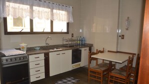 Une cuisine équipée d’une cuisinière, d’un évier et d’une table à manger avec des chaises.
