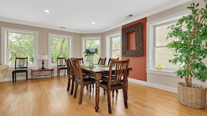 A dining room with a wooden table and chairs, large windows, and a potted plant. - Vintage charm with open concept floor plan, great for entertaining and families. (Chicago)