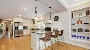A modern kitchen with white cabinets, stainless steel appliances, and a central island with bar stools. - Vintage charm with open concept floor plan, great for entertaining and families. (Chicago)