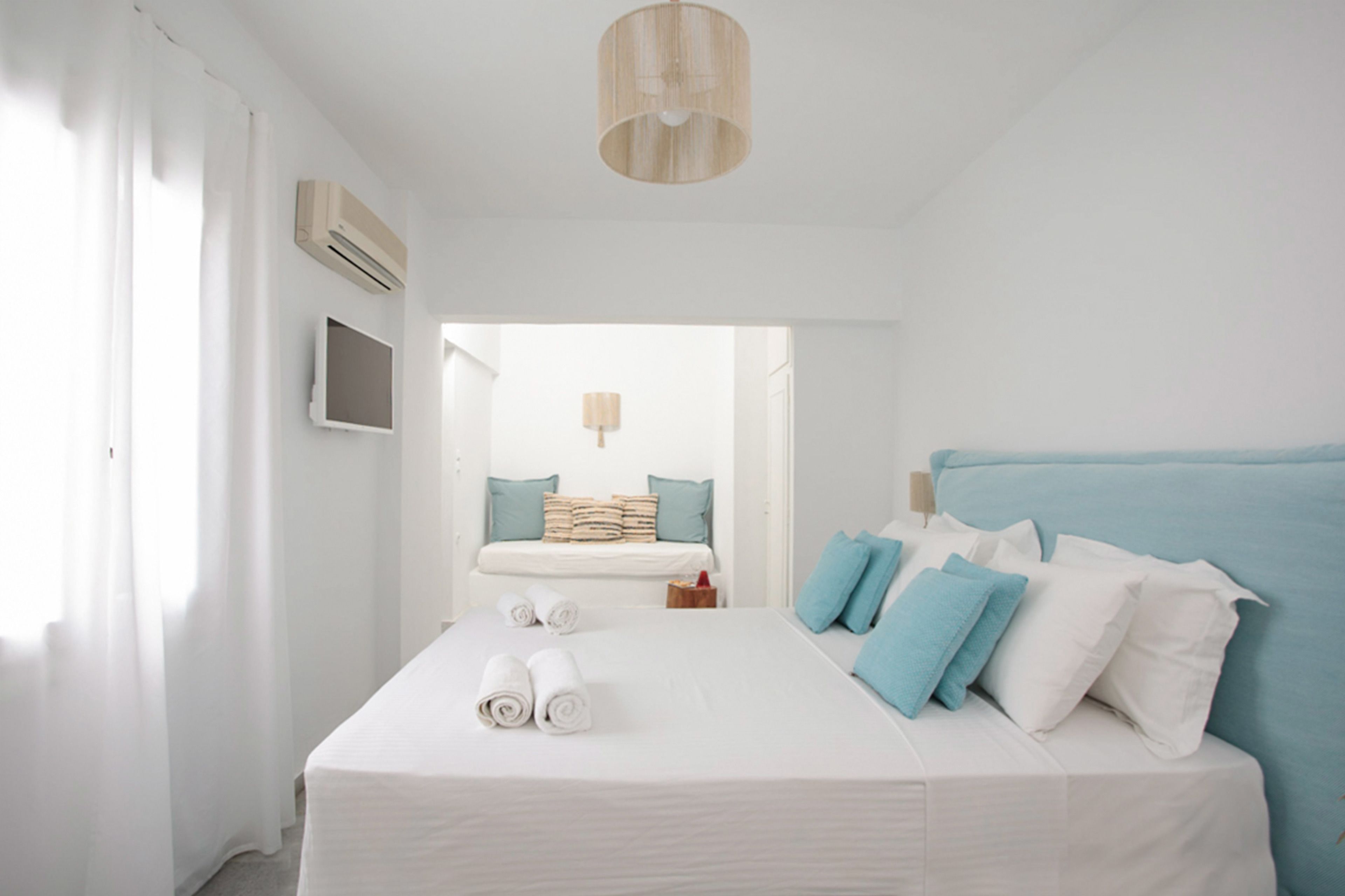 Una habitación de hotel moderna con una cama grande, un televisor de pantalla plana y una lámpara en el techo.