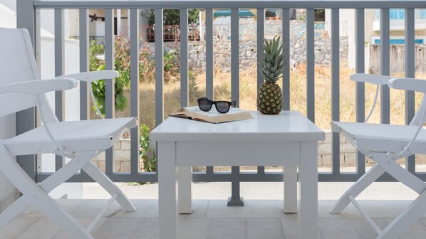 A white table with two chairs, a pineapple, and a pair of sunglasses on it.