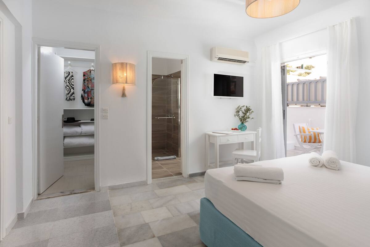 Una habitación de hotel moderna con cama, escritorio, ducha y armario.