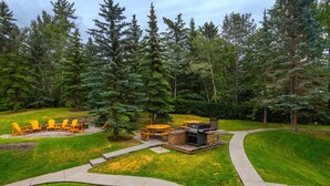 A backyard with a grill, outdoor seating, and a paved path. - Mountain View Cozy 2-Storey Chalet, 2 BR , 1.5 BTH, Hot Tub, BBQ (Harvie Heights)