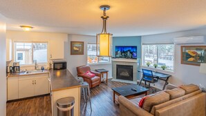 A modern living room with a fireplace, a sofa, a coffee table, and a television. - Mountain View Cozy 2-Storey Chalet, 2 BR , 1.5 BTH, Hot Tub, BBQ (Harvie Heights)