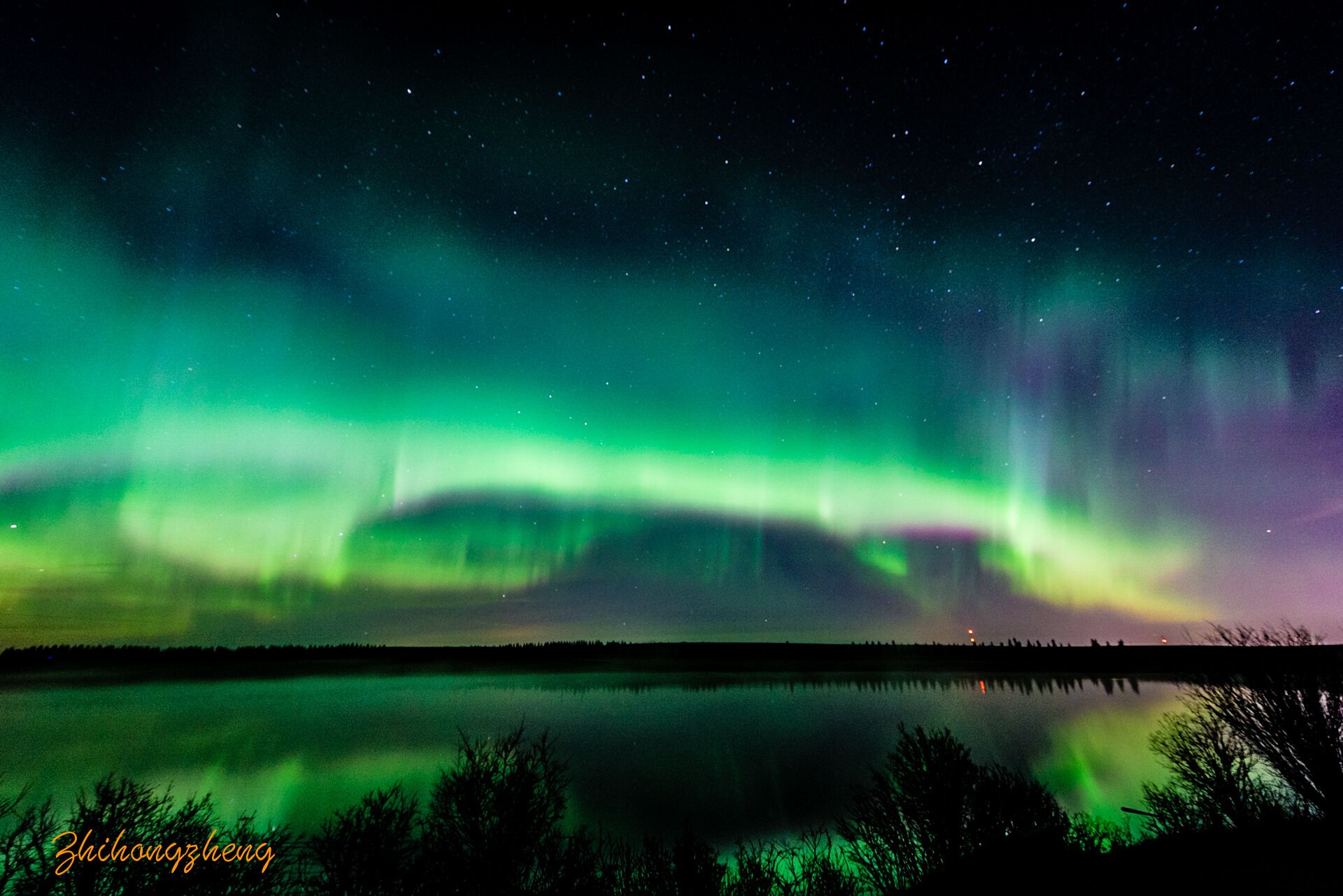 A night sky with the aurora borealis over a calm lake, reflecting the lights.