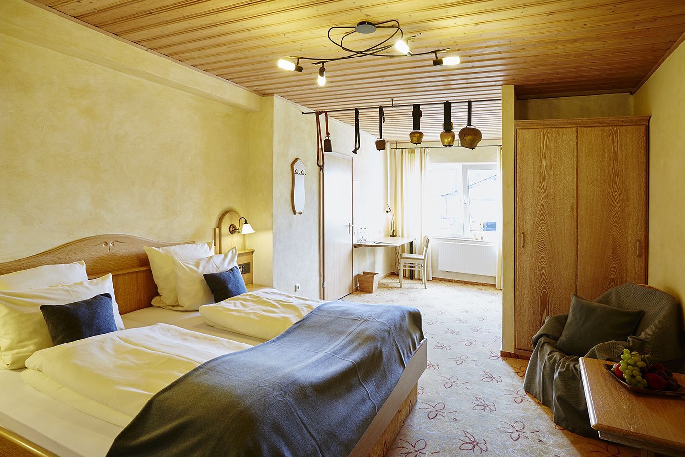 Un dormitorio con dos camas, un armario de madera, un escritorio y una silla.