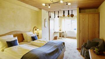 Un dormitorio con dos camas, un armario de madera, un escritorio y una silla.