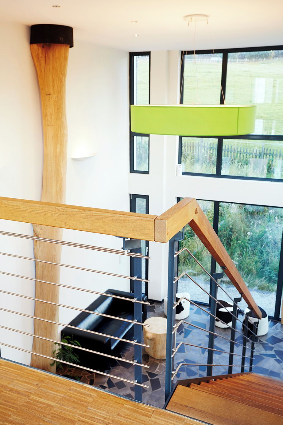 Ein modernes Interieur mit einer Holztreppe, Metallgeländern und Blick ins Grüne.