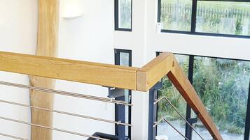 Ein modernes Interieur mit einer Holztreppe, Metallgeländern und Blick ins Grüne.