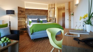Una habitación de hotel moderna con una cama grande, un escritorio con un teléfono, una silla y una pequeña mesa con manzanas.