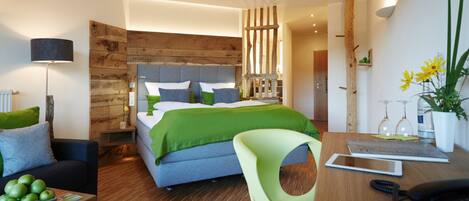 Una habitación de hotel moderna con una cama grande, un escritorio con un teléfono, una silla y una pequeña mesa con manzanas.