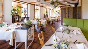Un restaurante con varias mesas dispuestas para comer, con manteles blancos y sillas con reposabrazos verdes.