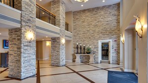 A spacious lobby with stone pillars, a tiled floor, and a staircase. - Updated Beachfront Condo - Beach View, Balcony, Pool, Tiki Bar, Hot Tub, Tram (Miramar Beach)