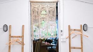 Una puerta con cortina de macramé, muebles de madera y un enchufe en la pared.