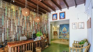 Una habitación con barra de madera, suelo verde y pared decorada con balaustradas de madera. Se observan cuadros enmarcados y una pintura en la pared.