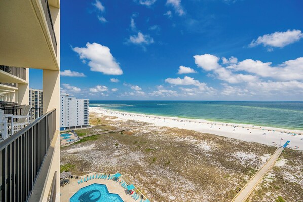 A high-rise hotel overlooking a beach with a swimming pool and a clear blue sky. - Lovely 3BR Gulf Front Condo - Phoenix VII 71205 (Orange Beach)