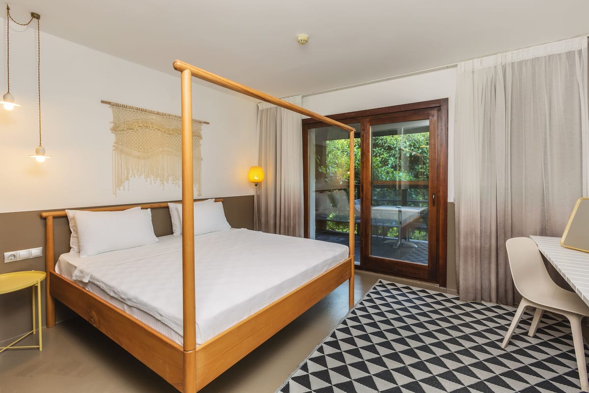 Una habitación con cama con dosel, una mesita, una silla y vistas al exterior a través de un ventanal.