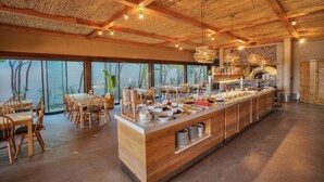 A spacious dining area with a long wooden counter, multiple seating arrangements, and large windows offering a view of the outdoors.