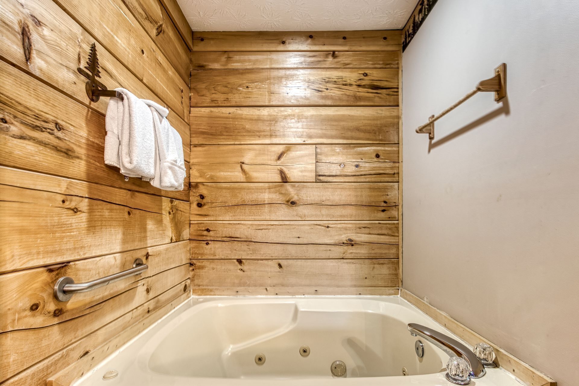 Une salle de bain aux murs lambrissés, équipée d’une baignoire, d’un porte-serviettes et d’une serviette accrochée au mur.