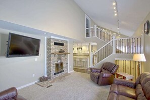 Cozy living area with a fireplace, flat-screen TV, and staircase to an upper level.