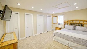 Un dormitorio con una cama, televisión montada en la pared y cabecero de madera.