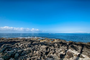 Une côte rocheuse bordée d’eaux d’un bleu limpide et s’étendant jusqu’à un horizon lointain.