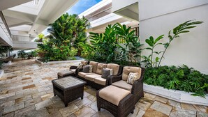 Un amplio patio interior con diseño moderno, que incluye un sofá modular grande, una mesa de centro y abundante vegetación.